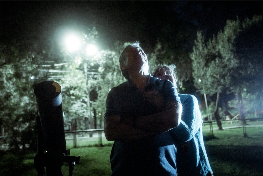 Personas reunidas de noche junto a un equipo óptico en el parque.